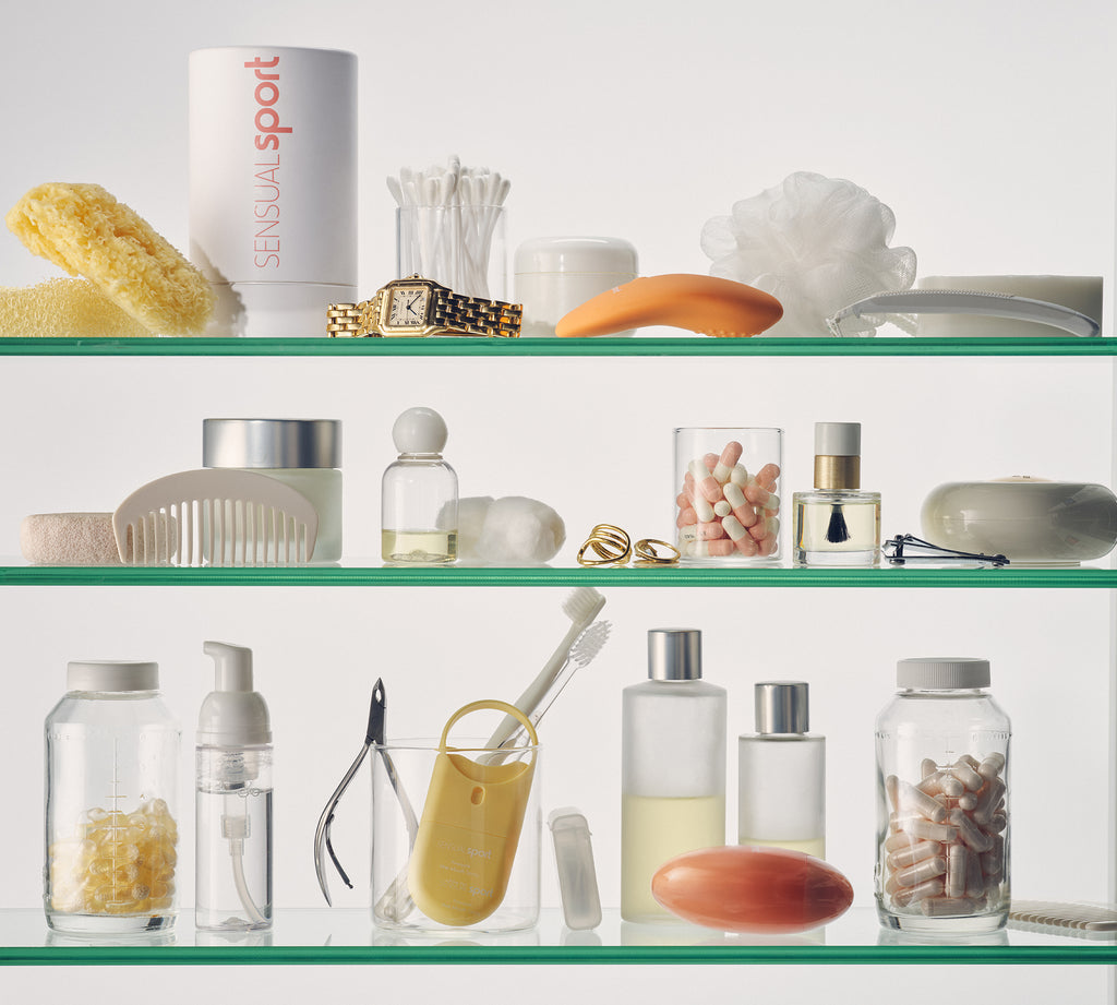 A neatly organized glass shelf with skincare, grooming, and wellness essentials in a clean, minimalistic style with neutral tones and soft pastels.